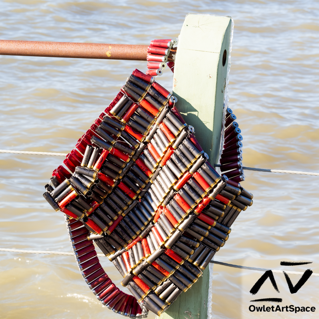 The "Bullet Backpack" piece hanging by one of the bandolier-style straps on a post. It is on a balcony in front of the lake.