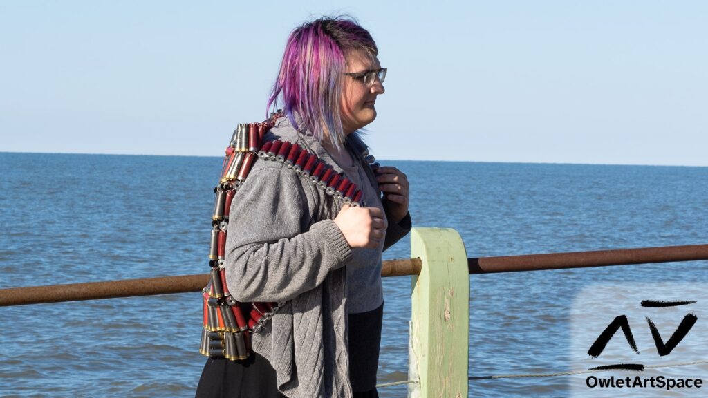 The artist wearing the "Bullet Backpack" piece. The aritist is facing to the right and holding onto the straps and staring off into the distance.