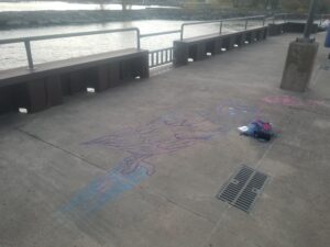 An angled shot of the lineart for the Owl Mural. Laying next to it is a blue bag. Visible in the background is the siderails and water.