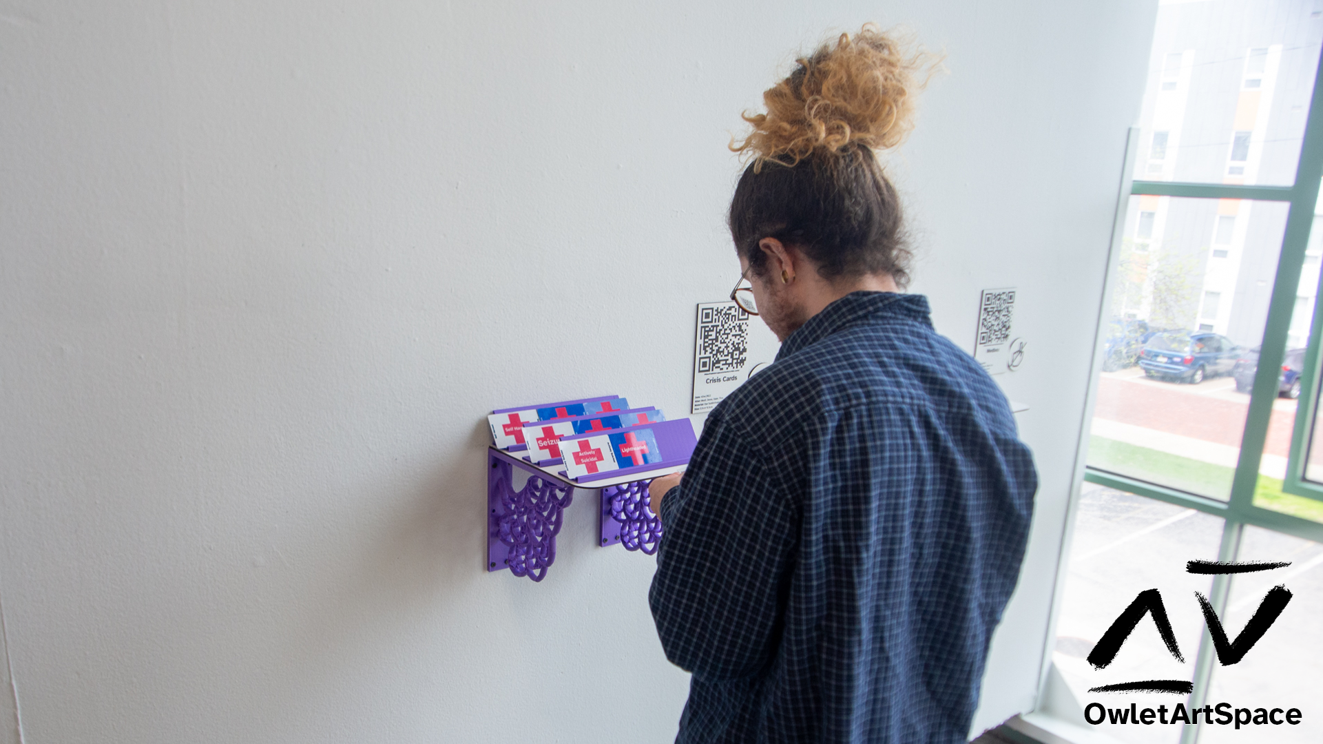 Nat holding one of the crisis cards. Others are displayed on stands on a shelf.