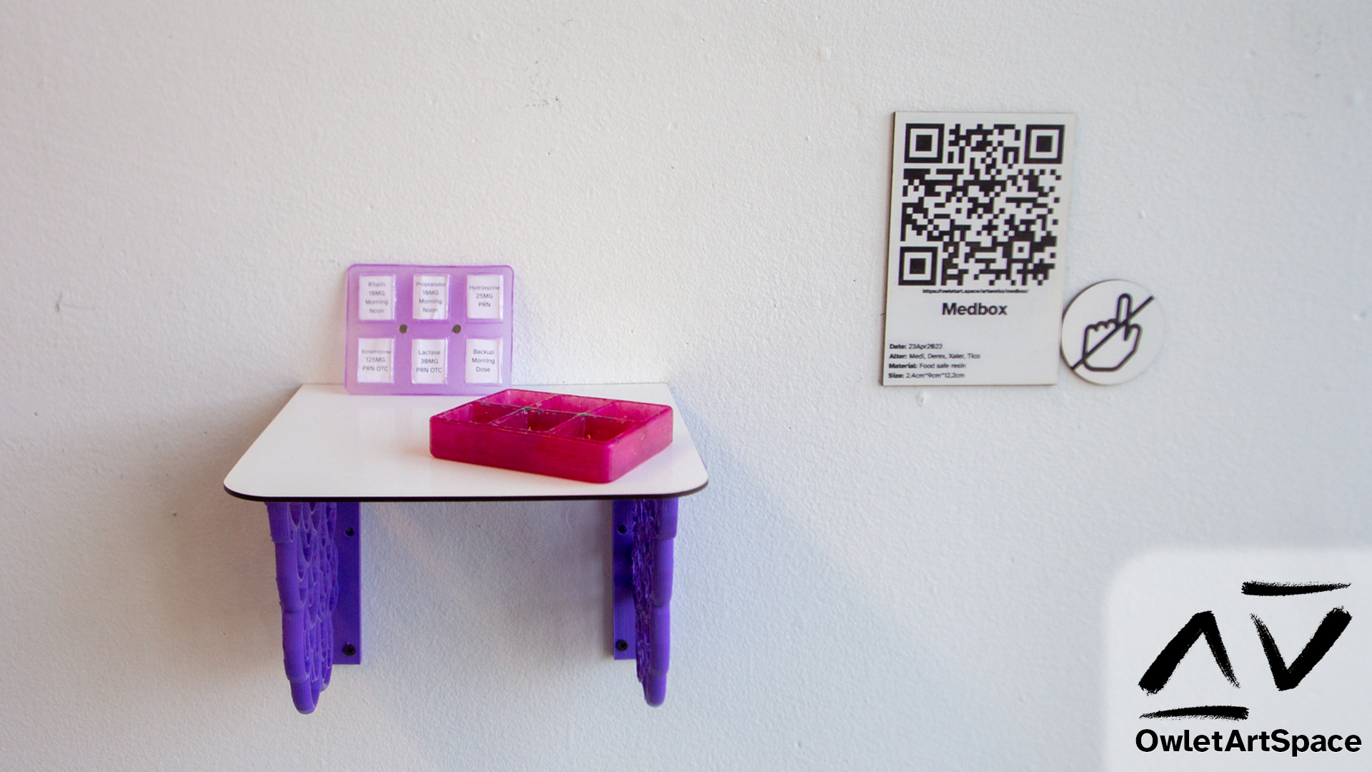 The medbox displayed open on a shelf. Next to it is a wall label with a QR code to the page you are currently reading.